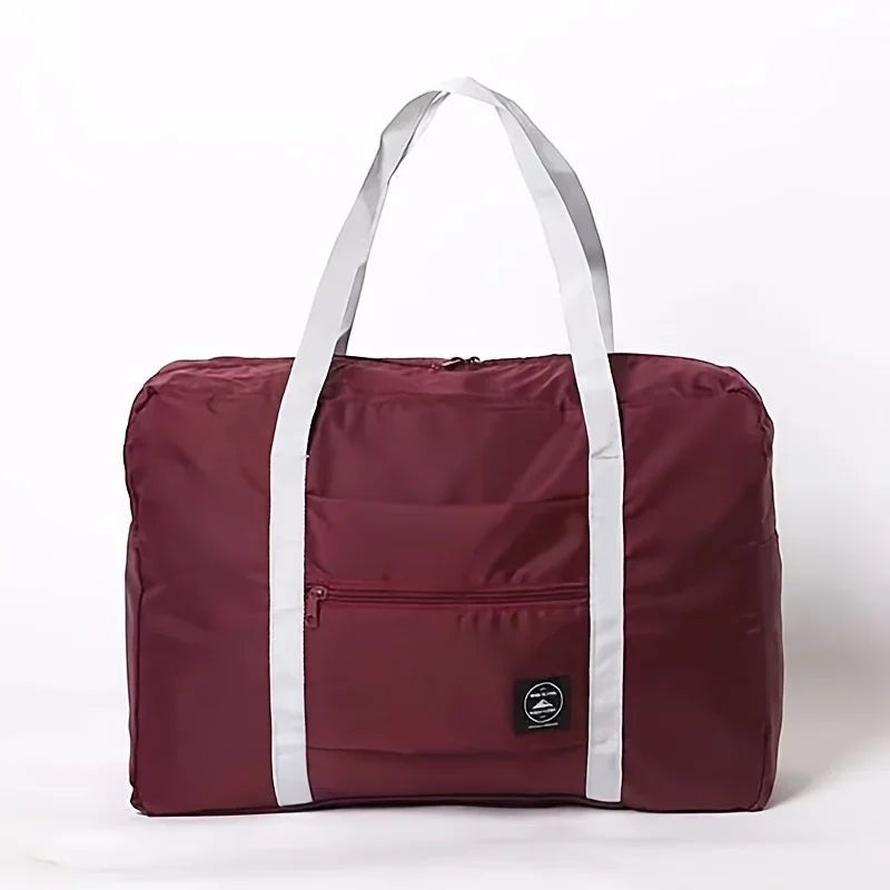 Bolsa de viaje plegable Variedad Online de nailon impermeable color burdeos con asas blancas y bolsillo frontal con cremallera.