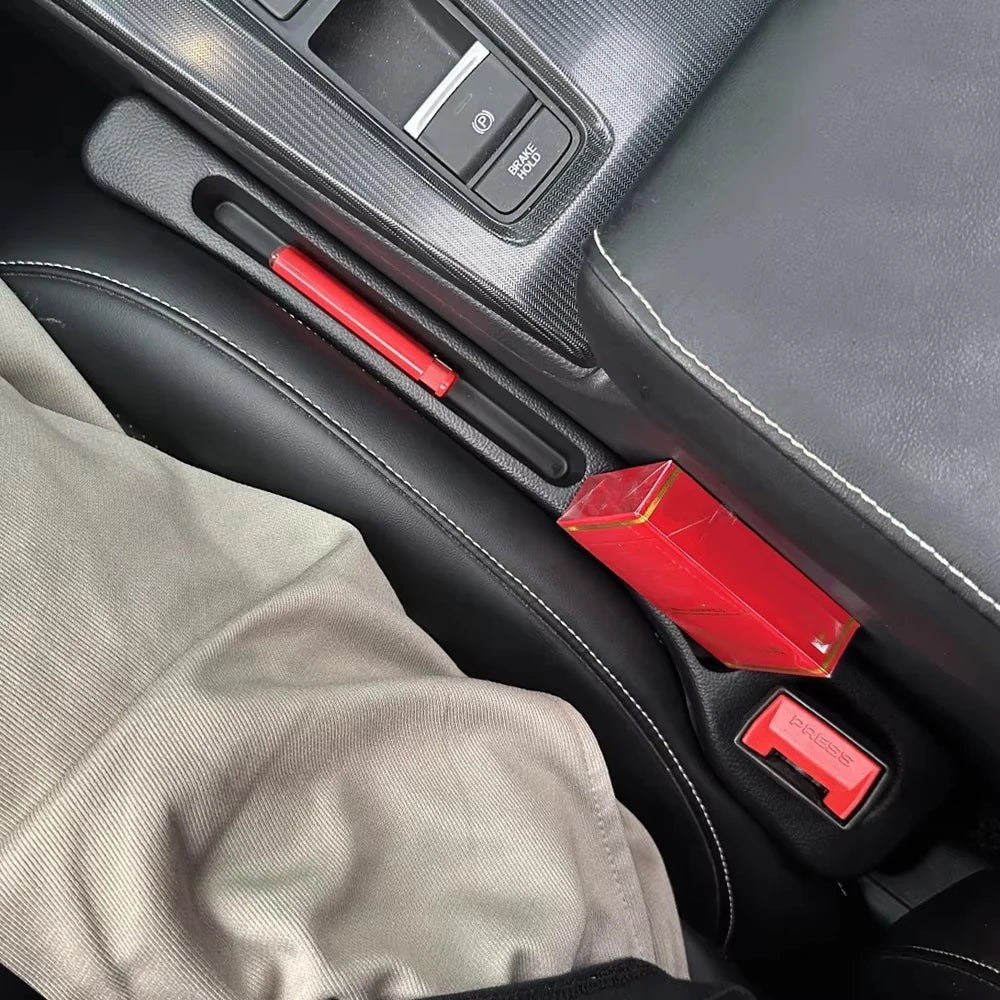 Organizador de huecos para asientos de coche Variedad Online, negro, con un bolígrafo rojo y una caja de cigarrillos roja en su interior.