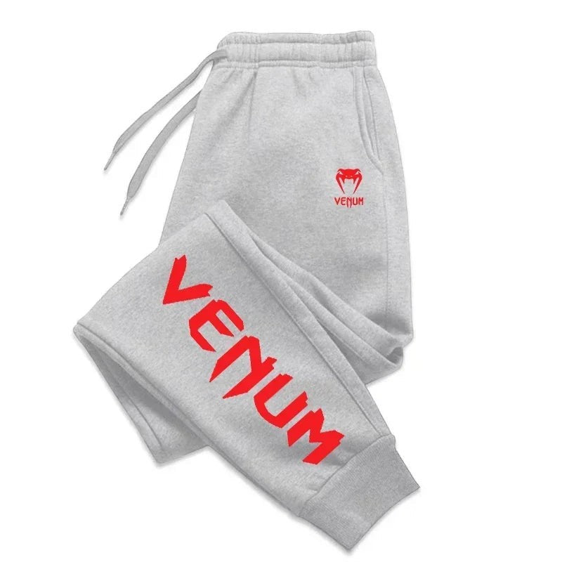 Variedad Online Pantalones de chándal grises para hombre con logo rojo de Venum en el muslo y estampado lateral.